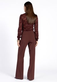 Bordeaux kanten top met lange mouwen, gecombineerd met hoge taille, wijdvallende donkerbruine broek. Soepele stof en op maat gemaakte pasvorm met subtiele details aan de achterkant.