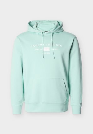 Vaaleansininen Tommy Hilfiger -huppari, jossa on etutasku, kiristysnyörit ja valkoinen teksti "Tommy Hilfiger American Classics Est. 1985".