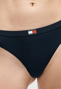 Σκούρα ναυτική εσώρουχα σε άτομο, με μικρό ορθογώνιο έμβλημα λογότυπου Tommy Hilfiger στο κέντρο του μπροστινού μέρος της μέσης.