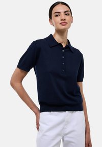 Polo shirt à manches courtes bleu marine avec un col, patte de boutonnage à cinq boutons et ourlet côtelé. Fabriqué en tissu doux et texturé.