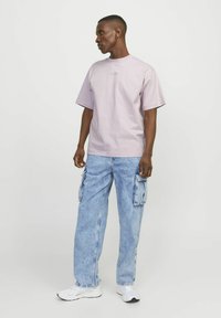 Ljuslila bomullströja med korta ärmar, rundad halsringning och minimalistisk grafik. Matchad med ljusblå denim cargobyxor.