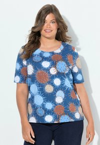 Camisa azul de manga corta con un patrón colorido y puntiagudo en naranja, blanco y azul claro. Hecha de tela suave con escote redondo.