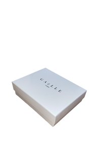 Scatola di cartone bianca con finitura lucida, caratterizzata dal testo "GAËLLE PARIS" in grassetto nero sulla parte superiore, forma rettangolare.