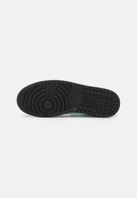 Podeszwa sneakerów Nike z textured czarnym gumowym wzorem. Charakteryzuje się okrągłymi i liniowymi rowkami dla lepszej przyczepności oraz trwałej konstrukcji.