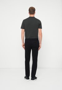 Tmavošedé polo tričko s krátkymi rukávmi, skombinované s čiernymi nohavicami slim fit a čiernymi teniskami. Oblečenie má neformálny, čistý dizajn.