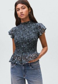 Top peplum smockato con stampa floreale blu e maniche corte arricciate. Realizzato in tessuto leggero, presenta un colletto alto e un design strutturato.