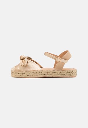 Nud espadrille sandal med en teksturert stoffoverdel, knyttet detalj ved tåen, og en juteinnpakket plattformsåle. Justerbar ankelstropp.