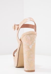 Chunky high-heeled sandal with ankle strap, covered in pink and gold floral brocade fabric, displayed against a plain white background.