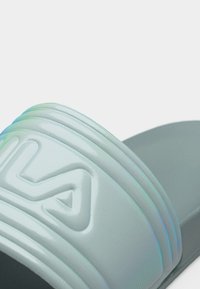 Κοντινό πλάνο γκρι σαγιονάρας με υφασμένη λουρίδα, με ανάγλυφο σχέδιο σε σχήμα στυλιζαρισμένου "H".