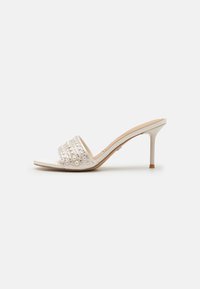 Bílé otevřené sandály s ozdobnými kor�álky, s vysokým stiletto podpatkem a hladkou strukturou. Minimalistický design s akcentními detaily.
