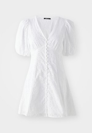 Robe en coton blanc avec manches bouffantes, décolleté en V, fermeture à boutons et motif de broderie florale. Silhouette en A et tissu texturé.