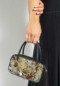 Black handbag with gold and silver snake print, featuring a chain with decorative charms, small handles, and a glossy texture.