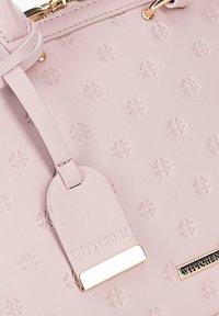 Lichtroze leren handtas met een geperst bloemenpatroon, voorzien van een afneembare tag en gouden hardware accenten.