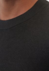 Schwarzer Strickpullover mit klassischem Rundhalsausschnitt. Glatte Textur und gleichmäßig verteilte Nähte, die die Qualität des Stoffes hervorheben.