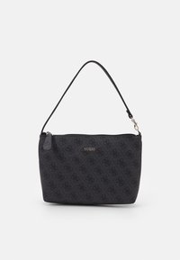 Sac à main Guess noir avec motif en relief, nom de marque doré, fermeture éclair et courte bandoulière amovible sur fond blanc.