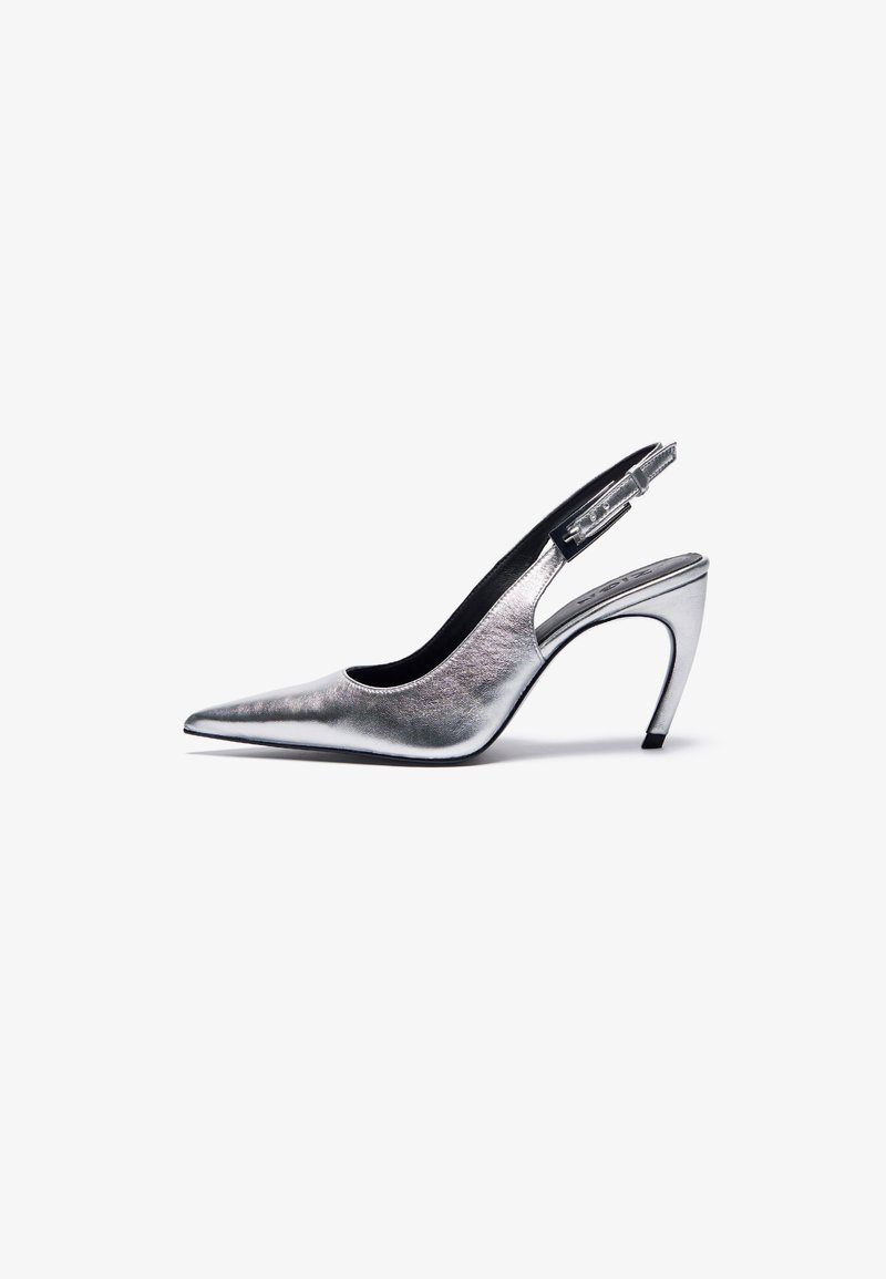 Sandalete slingback prateada com bico afilado, acabamento metálico brilhante e um salto alto esbelto. Fecho com fivela na parte de trás, textura suave.