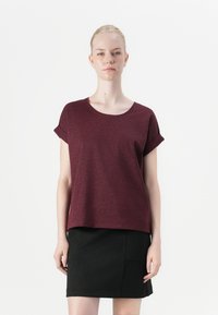 Mörkröd kortärmad topp med avslappnad passform och uppvikta ärmar, med en slät textur och rund halsringning, tillsammans med en svart kjol.