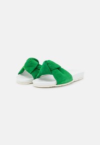 Sandales en daim vert avec un détail de nœud sur le dessus, semelle en plateforme blanche et finition texturée.