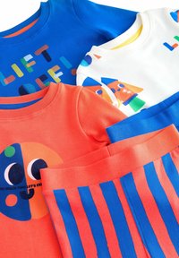 Set di abbigliamento colorato composto da una felpa blu con testo grafico, una felpa arancione con design di un volto e pantaloni a righe blu e rossi.