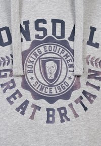 Grå hættetrøje med et stort grafisk print af "Lonsdale," en boksehandske og "Great Britain" i mørke farver, samt dekorative elementer.
