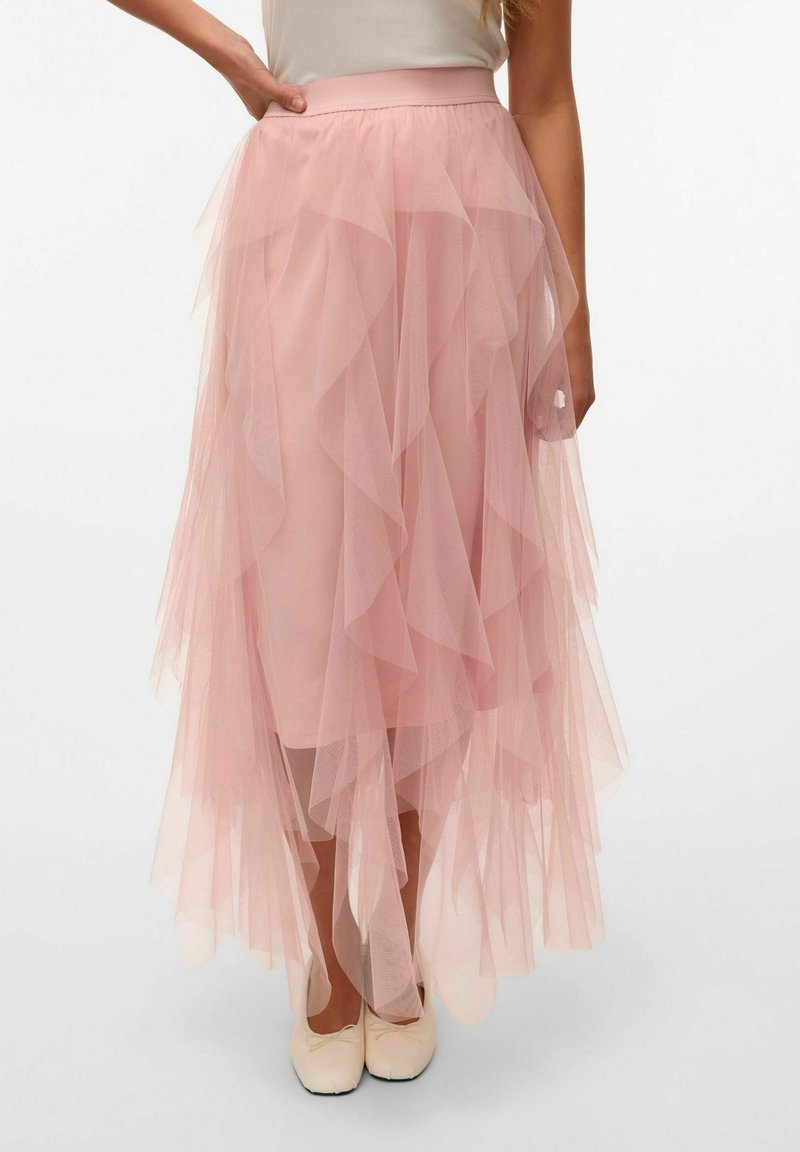 Ampia gonna maxi in tulle rosa pallido con volantes sovrapposti, vita elasticizzata e texture trasparente, abbinata a ballerine chiare.