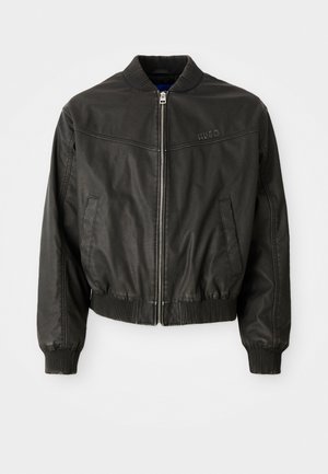 Must musta bomber jakk musta nahast, ribatreeritud krae ja mansettidega, eest lukuga, küljetaskudega ja rinnal diskreetne logo detail.