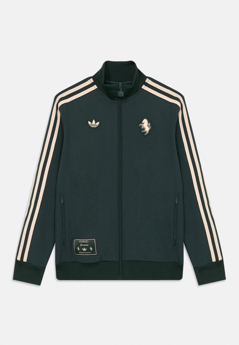 Dunkelgrüne Zip-up Trainingsjacke mit beigen drei Streifen an den Ärmeln, Adidas-Logo, Pferde-Patch und mit Reißverschluss versehenen Seitentaschen.