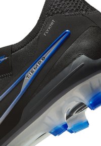 Schwarzer Fußballschuh mit Flyknit-Obermaterial, ausgestattet mit blauen Akzenten und silbernen Details. Durchsichtige Sohle mit blauen Stollen verbessert die Traktion.