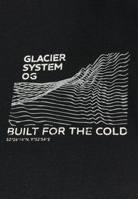 Camisa de tela negra con texto blanco: "GLACIER SYSTEM OG" y "BUILT FOR THE COLD" sobre un diseño de línea ondulada y coordenadas geográficas.