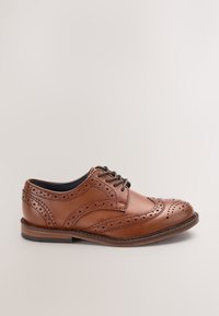 Bruine leren brogue nette schoen met geperforeerde details en zwarte veters, zijaanzicht op een neutrale achtergrond.