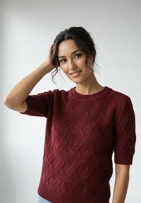 Bordowy sweter dziany z teksturowanym wzorem fal, krótkimi rękawami i okrągłym dekoltem, na jasnym tle.