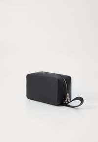 Borsa in pelle nera con superficie texturizzata, forma rettangolare, chiusura a zip e manico laterale per un facile trasporto.