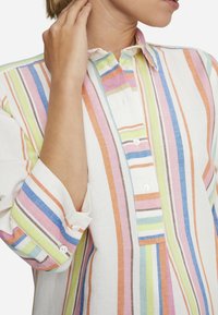 Linned skjorta med flerfärgade vertikala ränder, med knappslå och manschetter, i nyanser av rosa, blått, grönt och brunt.