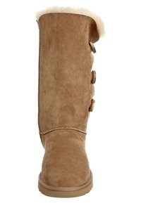 Kolanowe beżowe zamszowe botki z miękkim futrzanym mankietem, ozdobione trzema dekoracyjnymi guzikami na cholewce i płaską gumową podeszwą.