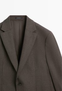 Blazer marrone su misura con bavero a lancia, chiusura con bottone singolo e tessuto strutturato. Interno con fodera liscia.