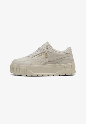 Beżowy sneaker na platformie marki Puma z teksturowaną podeszwą, sznurowanym zapięciem, złotym logo Puma oraz małym zawieszonym charmsem w kształcie gwiazdy na bocznej części.