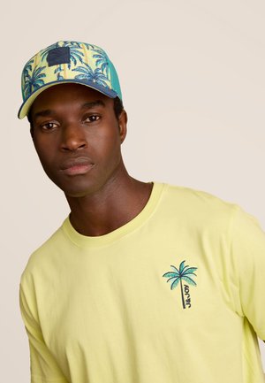 Geel shirt met korte mouwen met een geborduurde palmboom aan de linkerkant; wordt aangevuld met een blauwe en gele cap met palmboompatroon.