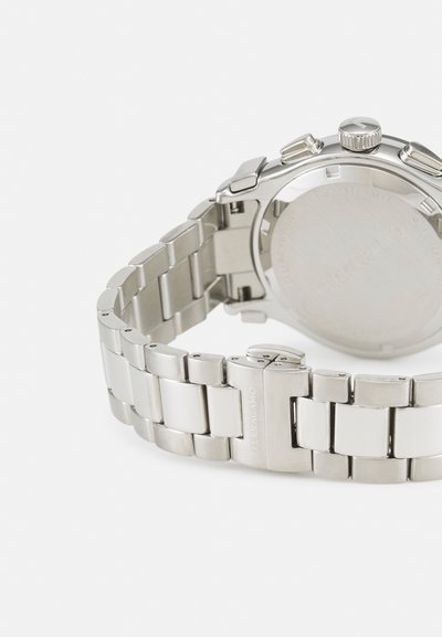 Silver stainless steel watch with a linked bracelet, a round case, three crowns, and engraved brand logo on the clasp. Smooth surface.
