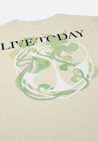 Crèmekleurig T-shirt met een grote graphic op de achterkant, met een groen draaiend ontwerp en de zin "LIVE TO DAY" in vetgedrukte zwarte letters.