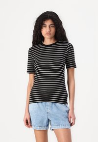 Black and white striped t-shirt, short sleeves, crew neckline, made of soft fabric, paired with denim shorts, relaxed fit.