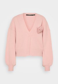 Rozā īss kardigāns ar V veida kakla izgriezumu, ribotām piedurknēm un dekoratīvu rozes detaļu kreisajā pusē. Mīksta tekstūra, ikdienišķa piegriezuma.