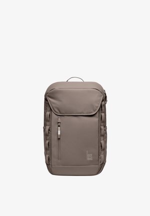 Mochila marrón con un bolsillo frontal con cremallera, correas acolchadas y una solapa superior plana. Fabricada con tela duradera, con un logotipo en la parte frontal.