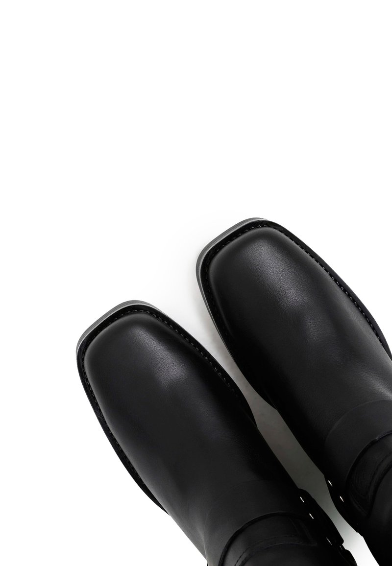 Czarne skórzane botki z kwadratowym noskiem, gładką fakturą i minimalnymi detalami przeszycia. Posiadają pasek i zapięcie w okolicach kostki.