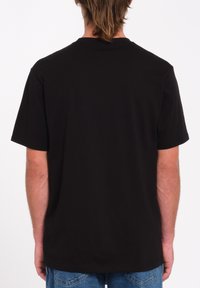 Schwarz Baumwoll-T-Shirt mit kurzen Ärmeln, Rundhalsausschnitt und einem schlichten Rücken. Keine sichtbaren Muster oder Hardware. Lässige Passform.