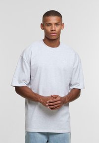 Light gray short-sleeve T-shirt with a round neckline and a small logo on the left chest. Made from soft cotton fabric. Casual fit.
