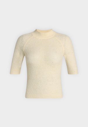 Πουλόβερ σε κρεμ απόχρωση με ριμπ ύφανση, κοντά μανίκια, ψηλό γιακά και εφαρμοστή σιλουέτα, παρουσιάζεται σε απλό ανοιχτό φόντο.