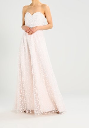 Olkaimeton, sydämenmuotoinen dekoltee-vaaleanpunainen mekko, jossa on kukkakuvioinen pitsikerros. Lattiaan ulottuva, laskeutuva siluetti hienostuneilla helmiäiskoristuksilla.