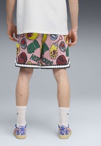Pantalones cortos de baloncesto multicolores con un fondo rosa, que presentan patrones divertidos, un dobladillo en zigzag negro y una textura de malla.