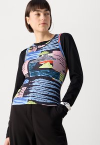 Long-sleeve top with a black fabric body and a colorful printed front featuring abstract shapes and text in blue, pink, and green.
