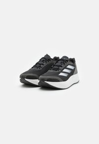 Scarpe da corsa nere con tomaia testurizzata, strisce bianche a contrasto, design elegante e intersuola imbottita per supporto.